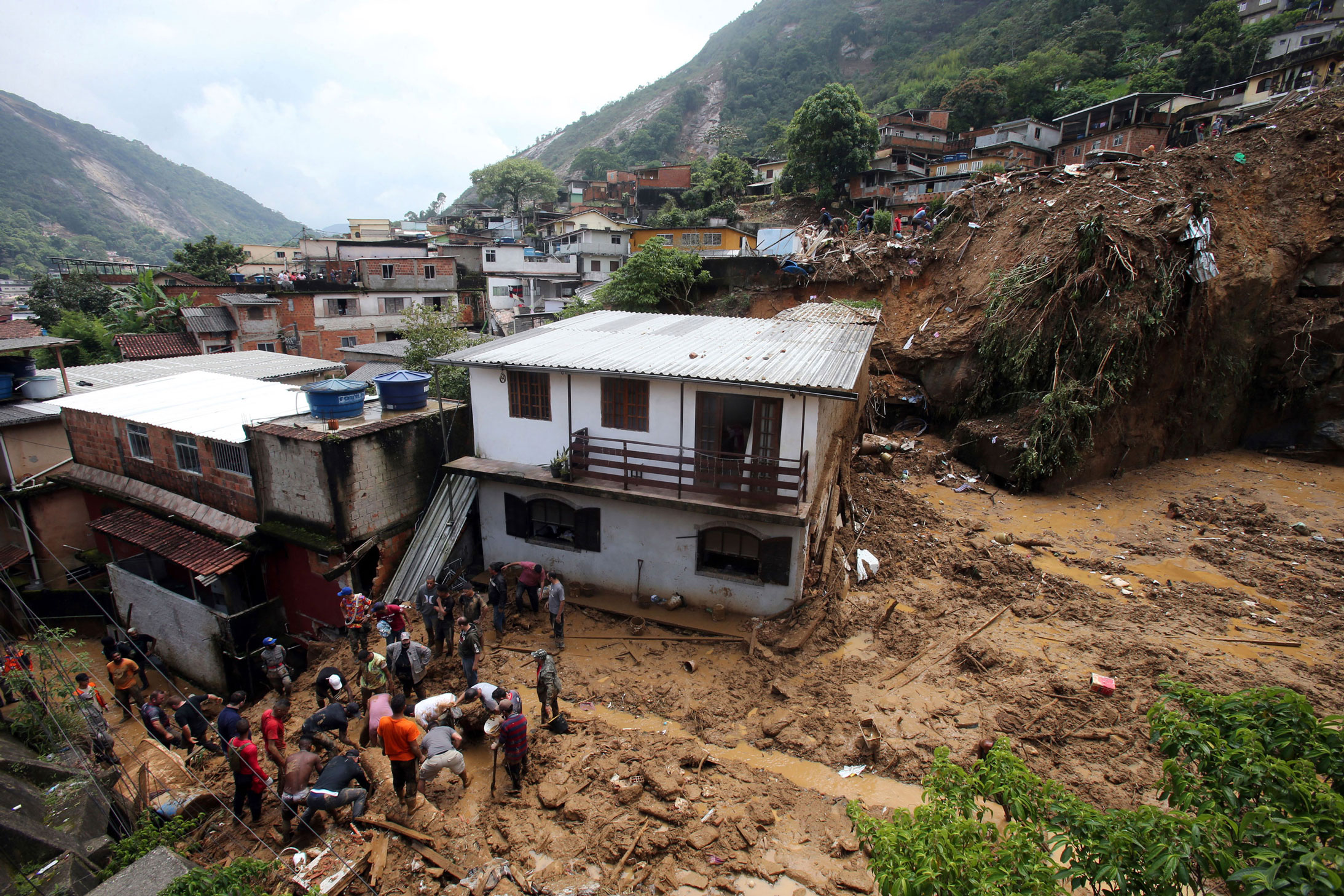 Residents ans rescuers search for victims after a landslide hit houses in Morro da Oficina in Petro...