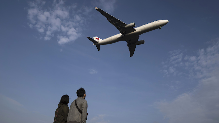 FILE: A couple looks at a China Eastern Airlines Corp. aircraft flying near Haneda Airport on April...
