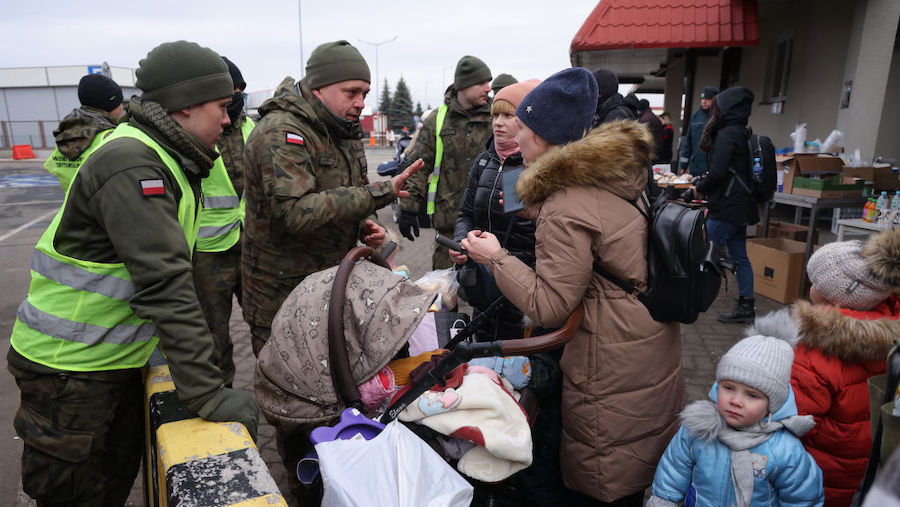 A Polish border guard speaks to women and children fleeing war-torn Ukraine and arriving in Poland ...