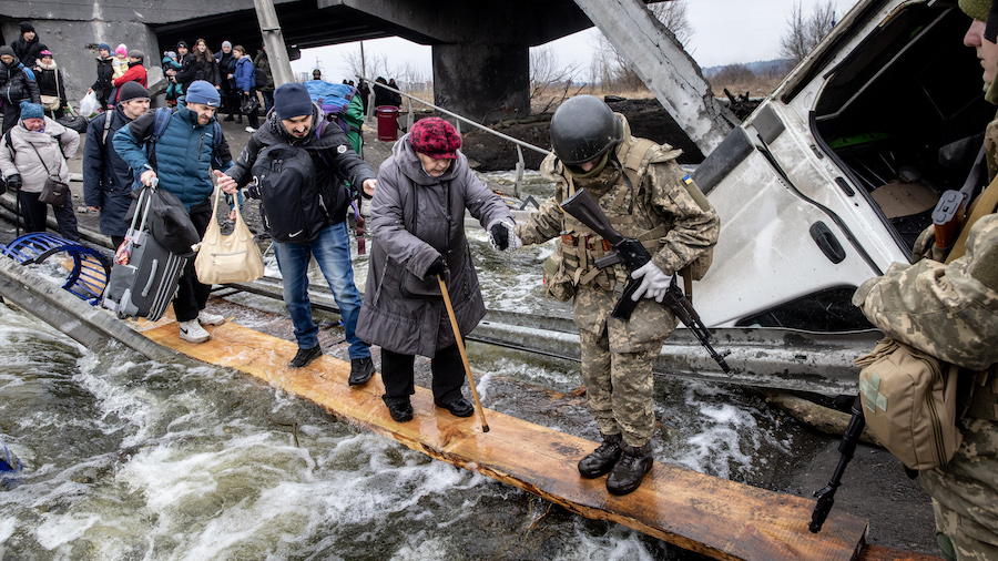 Residents of Irpin flee heavy fighting via a destroyed bridge as Russian forces entered the city on...