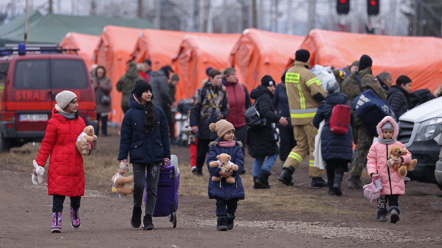 Women and children who fled from war-torn Ukraine walk among heated tents provided by Polish author...