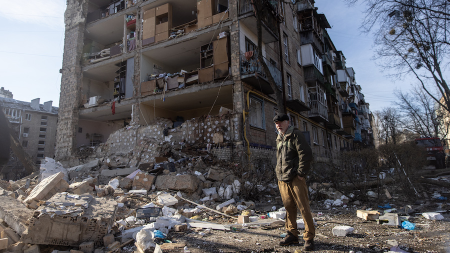 A man stands amid debris in front of a residential apartment complex that was heavily damaged by a ...