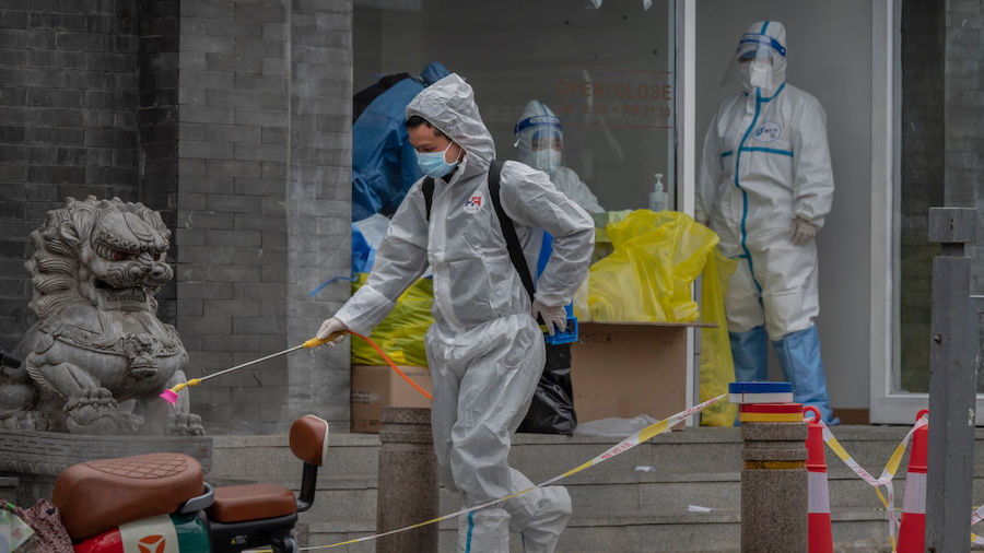 A health worker wears a  protective suit as he disinfects the area near a nucleic acid testing site...