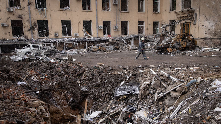 A firefighter walks past a rocket crater in the courtyard of the destroyed Kharkiv Regional State A...