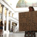 A woman holds a sign at the Utah State Capitol on Friday, March 25 when the Utah House and Senate voted to overturn a veto. The now-passed bill bars transgender athletes form participating in girls sports. (Kira Hoffelmeyer/KSL Radio)
