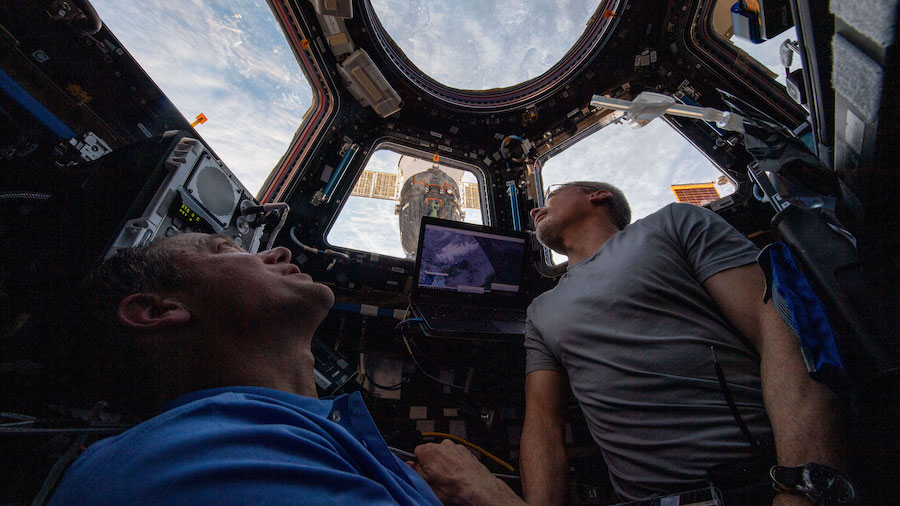 NASA astronauts Thomas Marshburn and Mark Vande Hei peer at the Earth below from inside the Interna...