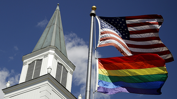 FILE - A gay pride rainbow flag flies along with the U.S. flag in front of the Asbury United Method...