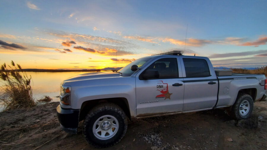 A Utah Division of Wildlife truck is parked before a sunset in Utah....
