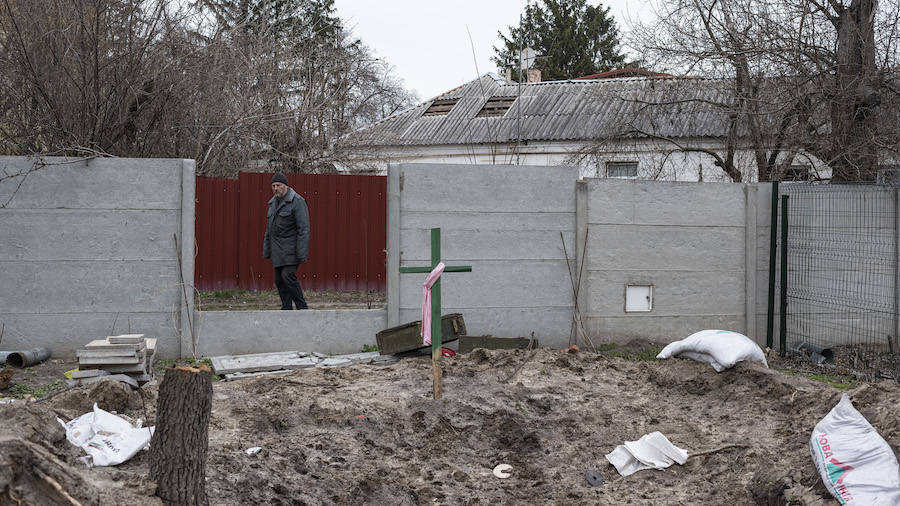 Kostiantyn, 63, stands by an abandoned military vehicle position where his neighbors buried four pe...