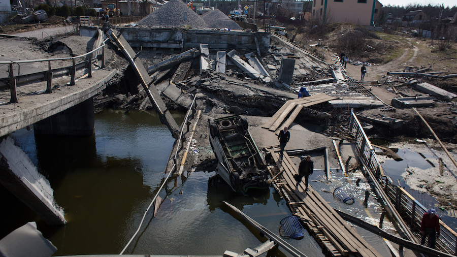 People cross the destroyed bridge to the city on April 7, 2022, in Irpin, Ukraine. The Russian retr...