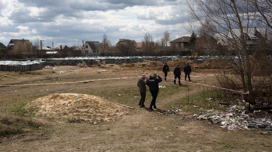 Police officers walk into the mass grave site on April 12, 2022 in Bucha, Ukraine. The Russian retr...
