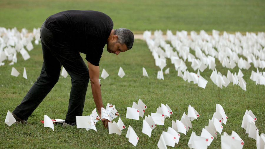 Dr. Debjeet Sarkar places 63 flags into the ground to represent the patients he cared for who died ...