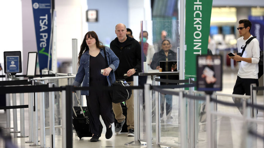 Airline passengers without face masks prepare to enter a security checkpoint at San Francisco Inter...