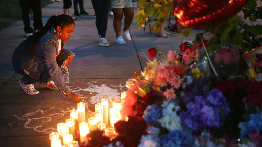 A woman chalks a message at a makeshift memorial outside of Tops market on May 15, 2022 in Buffalo,...