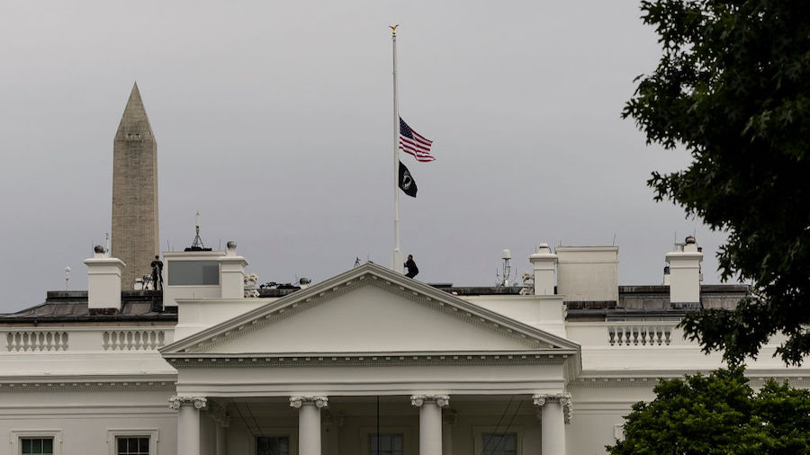 A U.S. Secret Service officer lowers the American flag to half staff over the White House following...