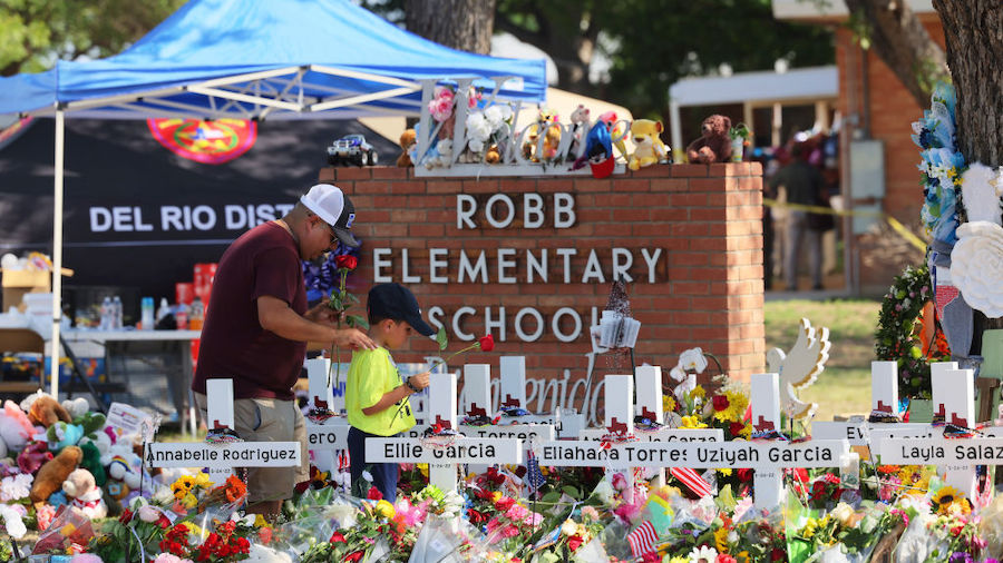 A man and a child pay their respects at a memorial to the victims of the Robb Elementary School mas...