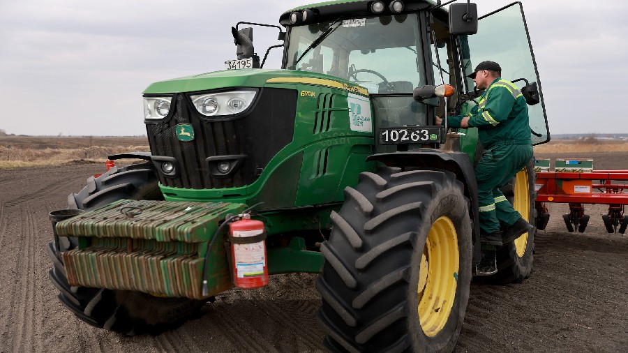 Ukrainian farmer Morda Vasyl steps into the cab of a John Deere tractor. (Credit: Joe Raedle/Getty ...