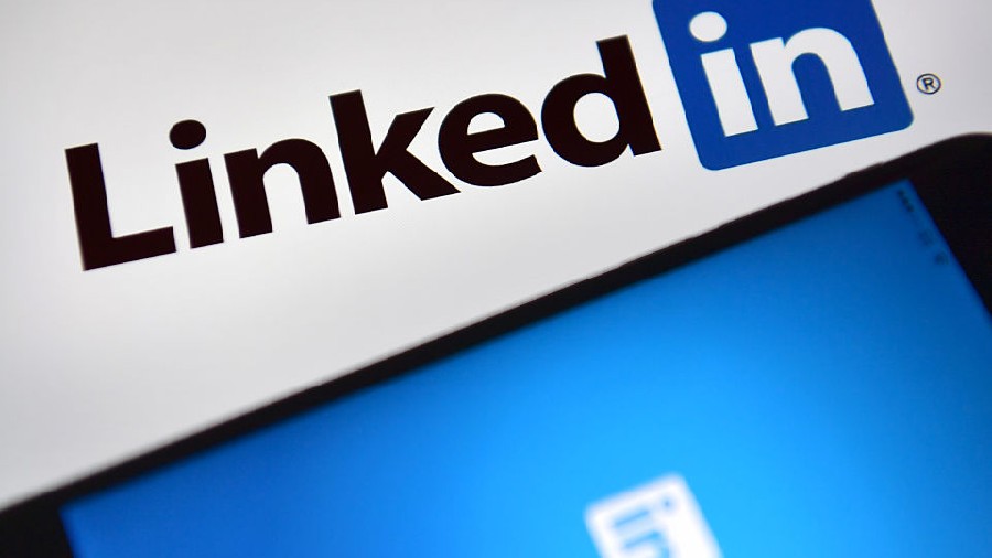 LONDON, ENGLAND - AUGUST 03: LinkedIn logos are displayed on an iPhone and computer screen on Augus...