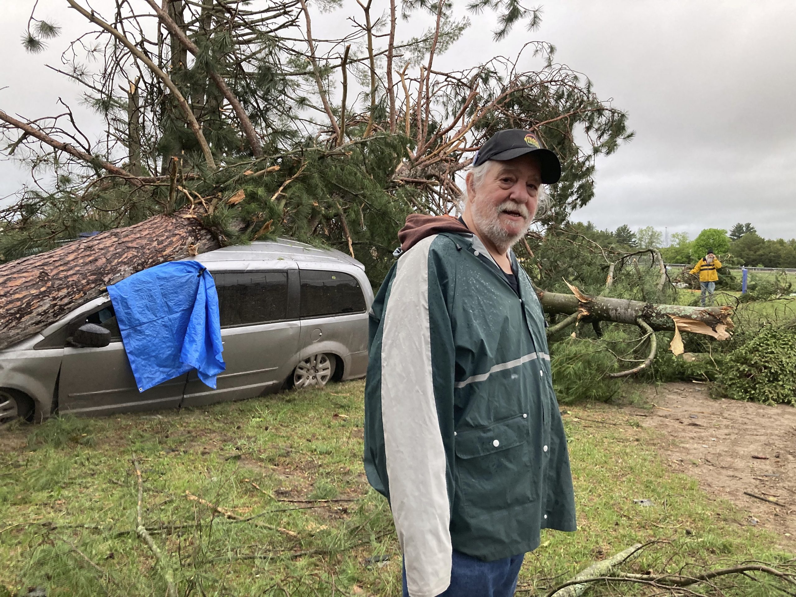 Jack Elliott stands beside his van that was struck by a tree during a tornado in Gaylord, Mich., Fr...