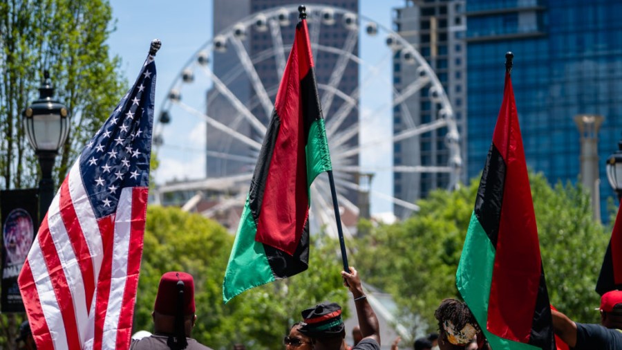 ATLANTA, GA - JUNE 18: People raise American and Pan-African flags while marching in the Juneteenth...