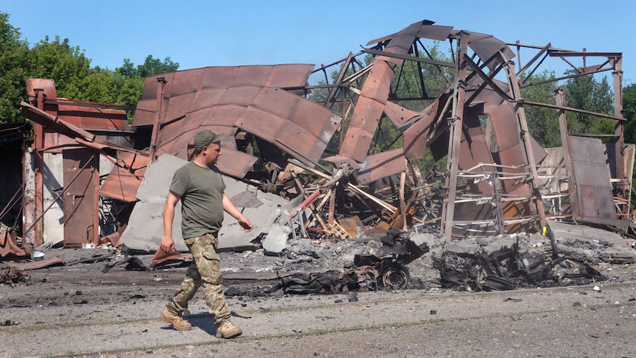 Soldiers survey damage and salvage items after a projectile and subsequent fire destroyed a warehou...
