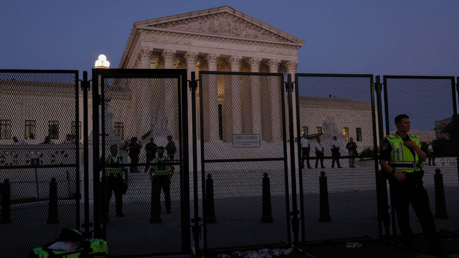 Law enforcement officers stand inside the secure perimeter of the U.S. Supreme Court Building as pr...