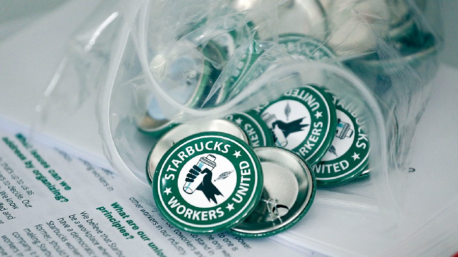 Pro-union pins sit on a table during a watch party for Starbucks' employees union election, Dec. 9,...