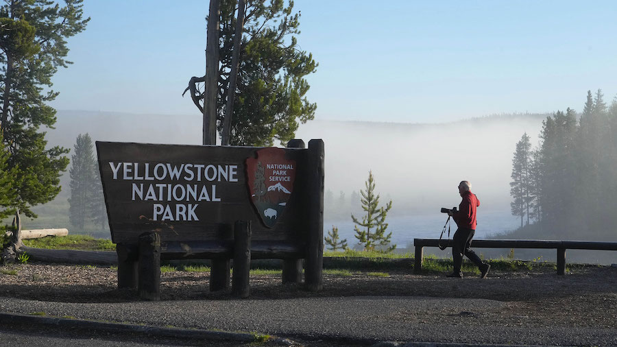 A man takes a picture at the south entrance of Yellowstone National Park, as he waits to gain entry...