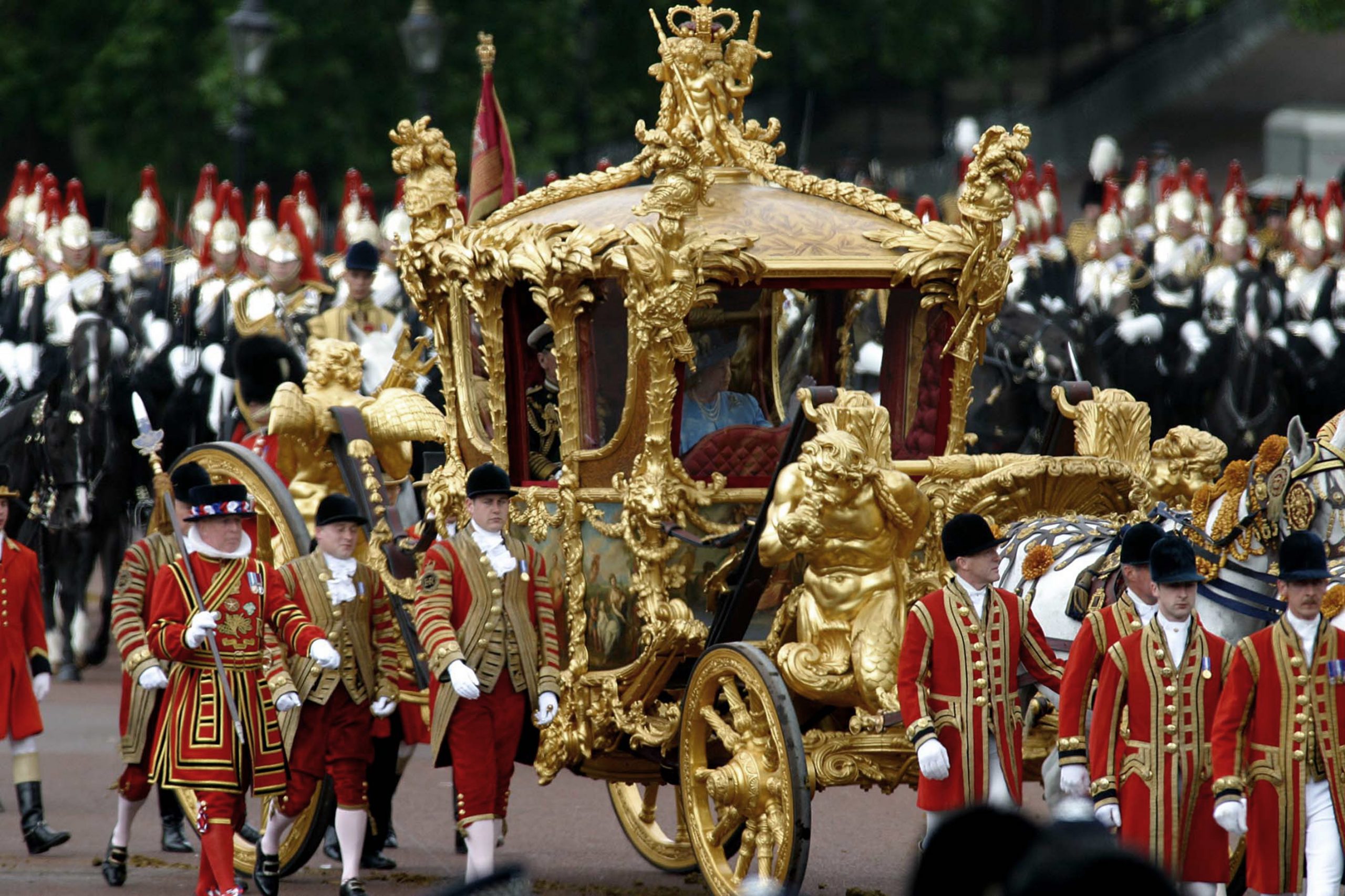 Queen Elizabeth II emerges through the gates of Buckingham Palace on her ceremonial journey through...