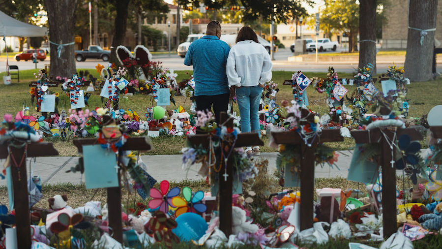 A couple from the nearby town of Del Rio, TX pays their respects at a memorial for the 21 victims o...
