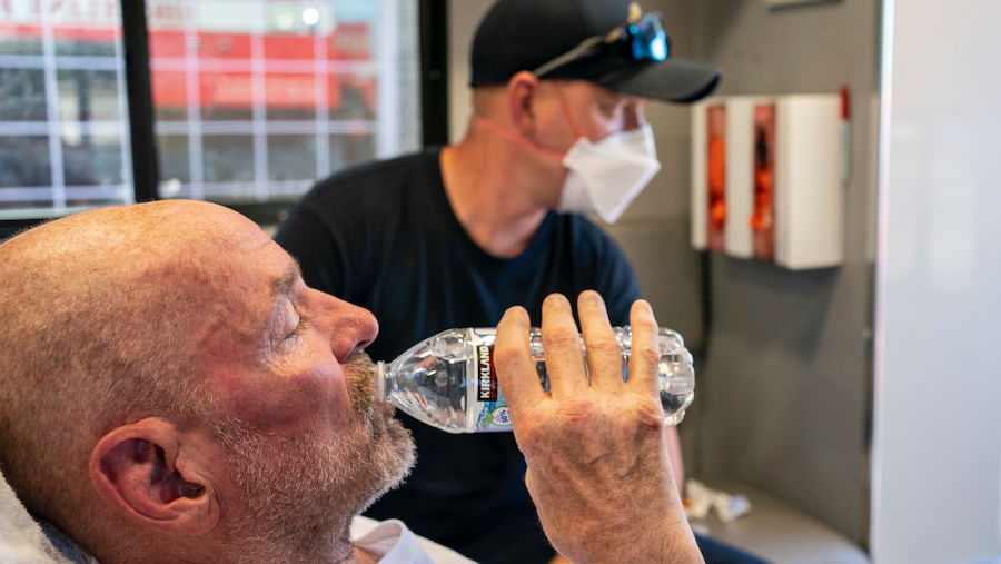 A homeless man showing symptoms of heat exhaustion drinks water in an ambulance as Ryan Horner, a f...