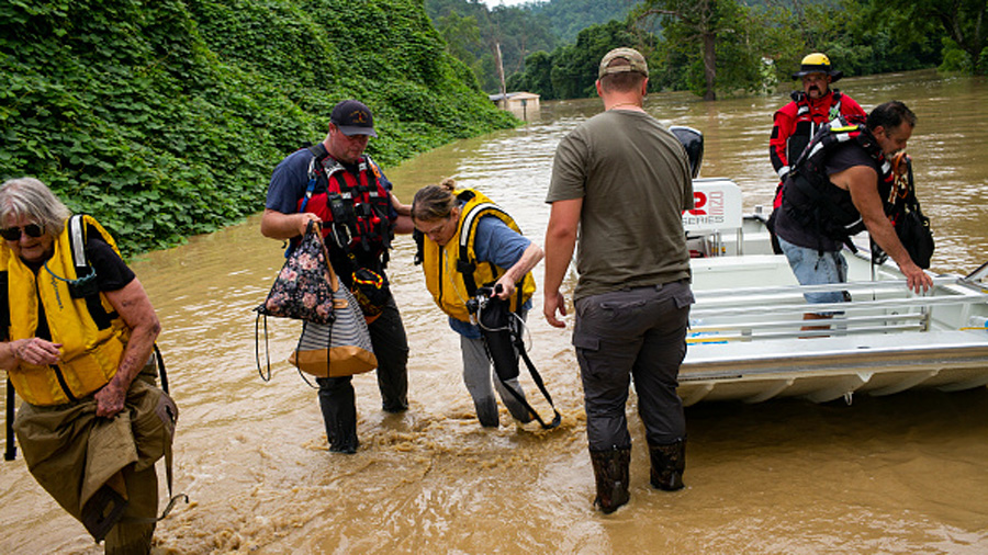QUICKSAND, KY - JULY 28: Members of a rescue team assist a family out of a boat on July 28, 2022 in...