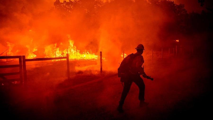 A firefighter runs to extinguish flames from the Oak Fire in Mariposa County on Friday. (Noah Berge...