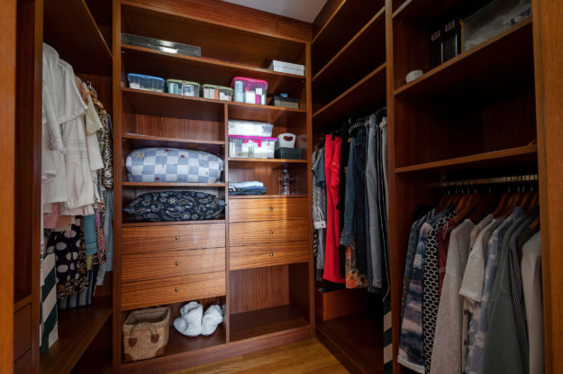 Modern wooden wardrobe with clothes in walk in closet