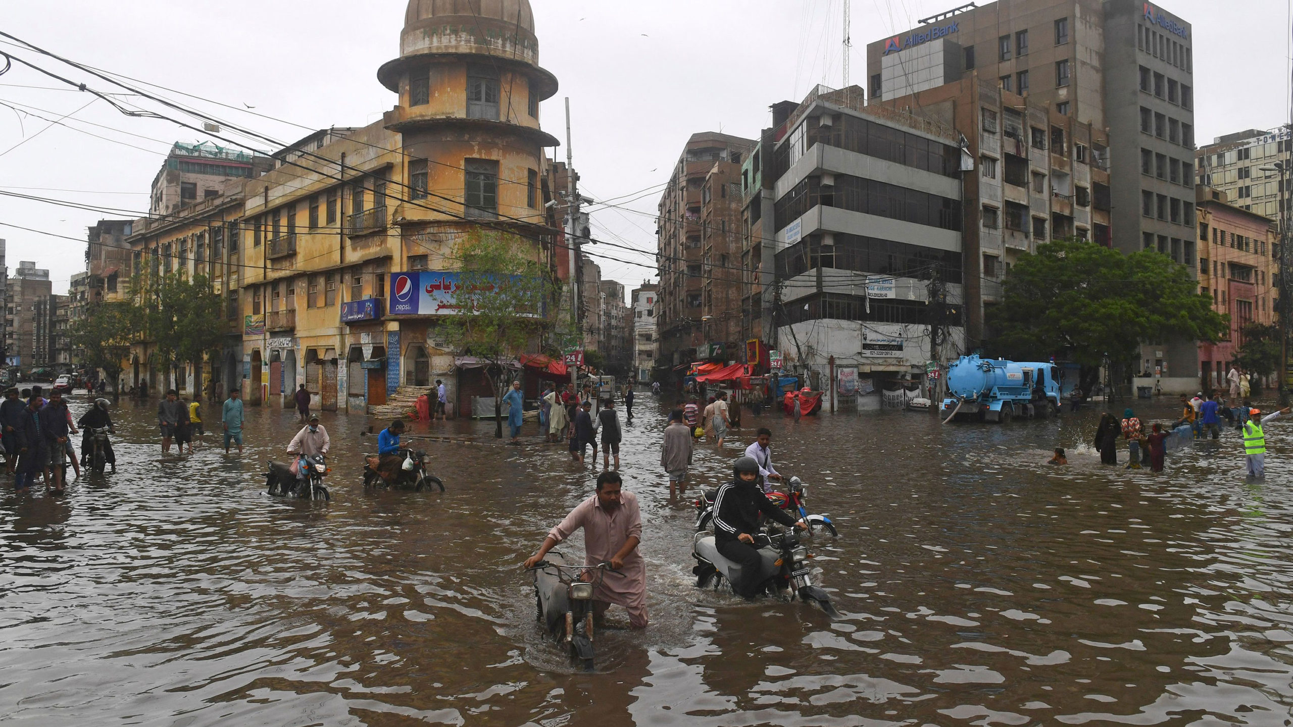 TOPSHOT - People wade across a flooded street after heavy monsoon rainfall in Karachi on July 25, 2...