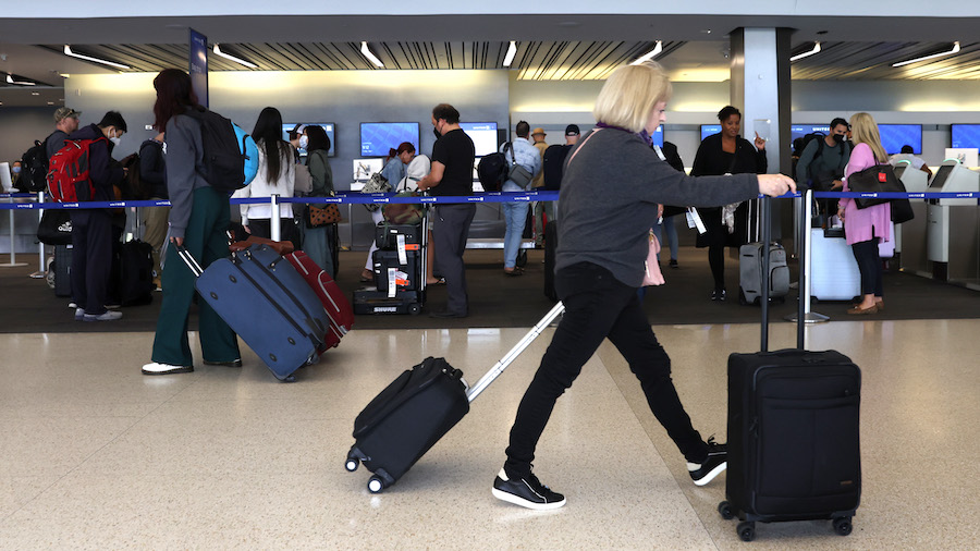Travelers walk with their luggage at San Francisco International Airport on July 1 in San Francisco...