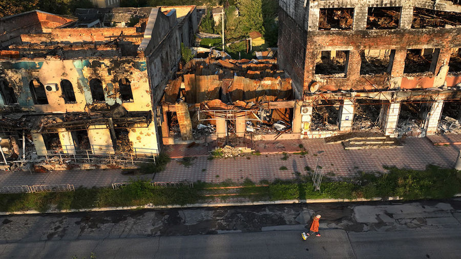 In an aerial view, a woman walks by a destroyed building on September 23, 2022 in Izium, Ukraine. I...