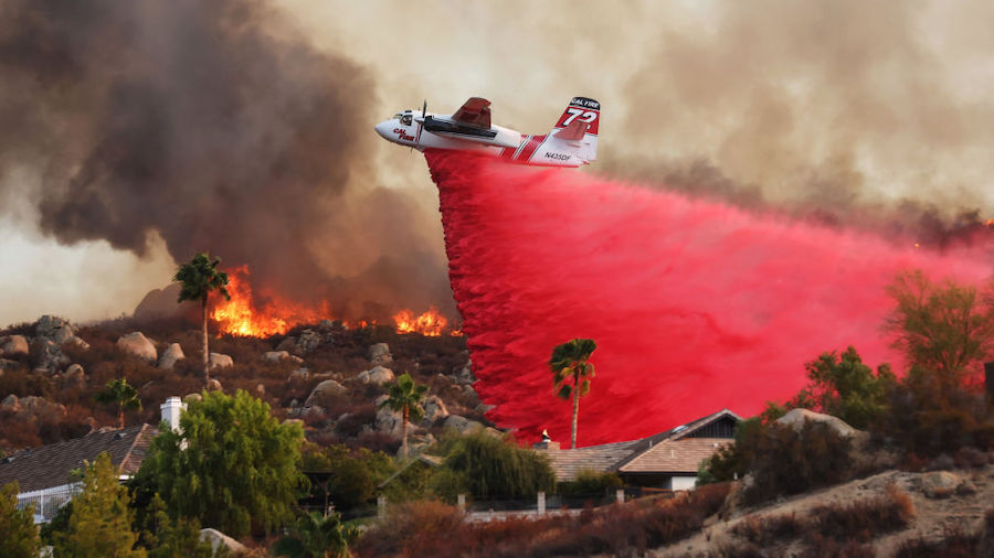 A firefighting aircraft drops fire retardant as the Fairview Fire burns near hillside homes on Sept...