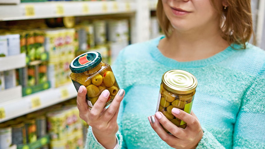 Woman chooses canned olives in the grocery store. (File photo)...