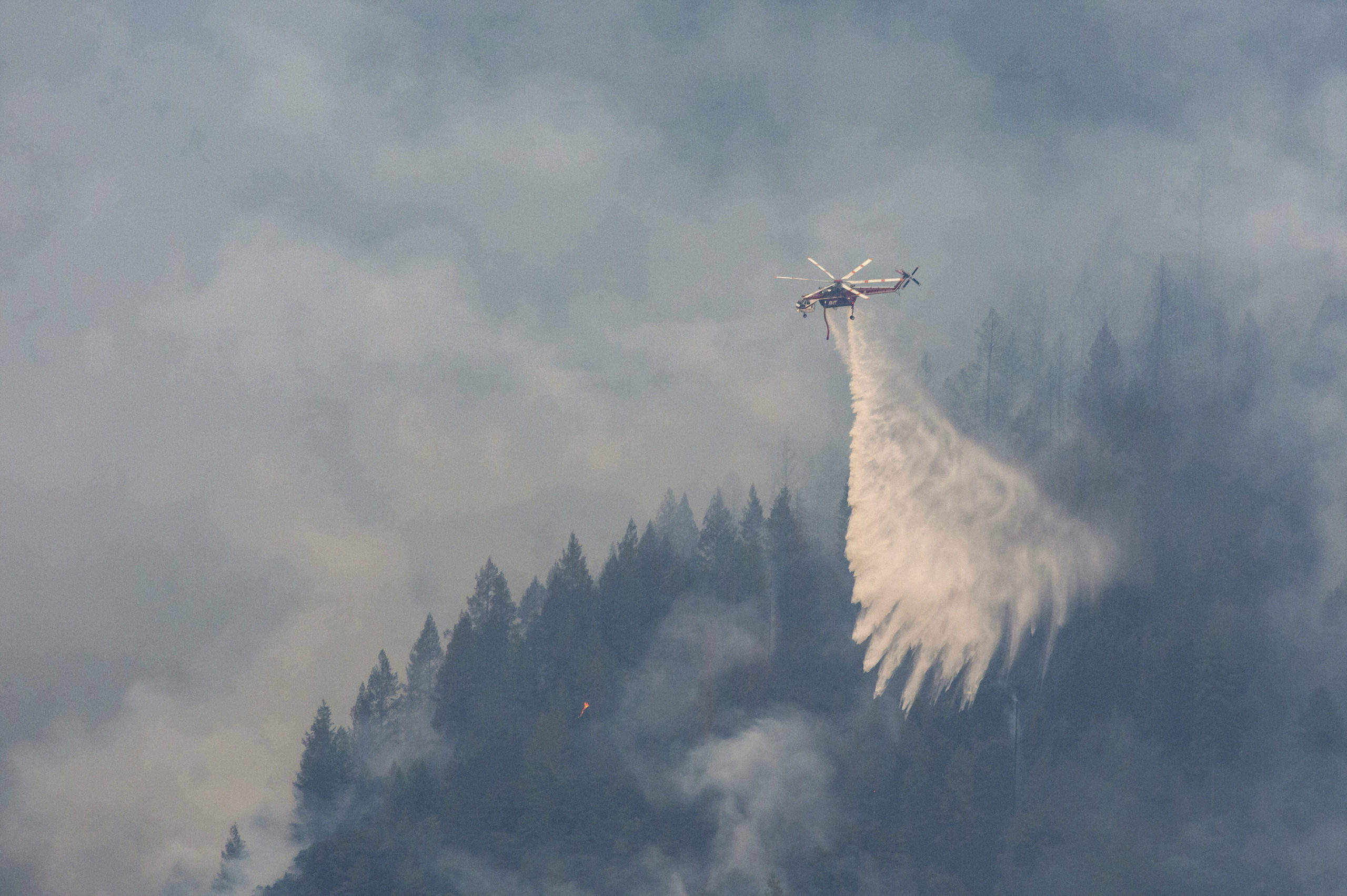 A Sikorsky S-64 "Skycrane" drops water on a ridge near Baltimore Mine Road during the Mosquito Fire...