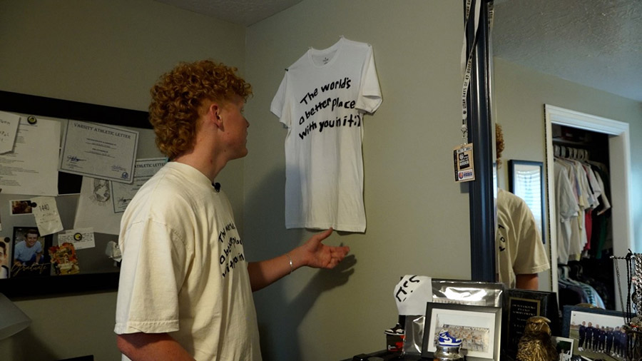 Jackson Eyre showing his shirt with "The world’s a better place with you in it." message....