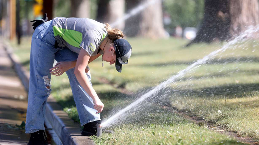 Riley Niederhauser, a Salt Lake City Public Lands Department crew member, repairs sprinklers in Lib...