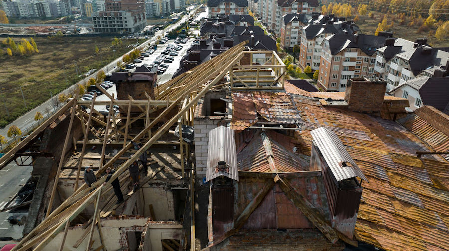 Construction workers rebuild a roof on an apartment building destroyed from shelling by the Russian...