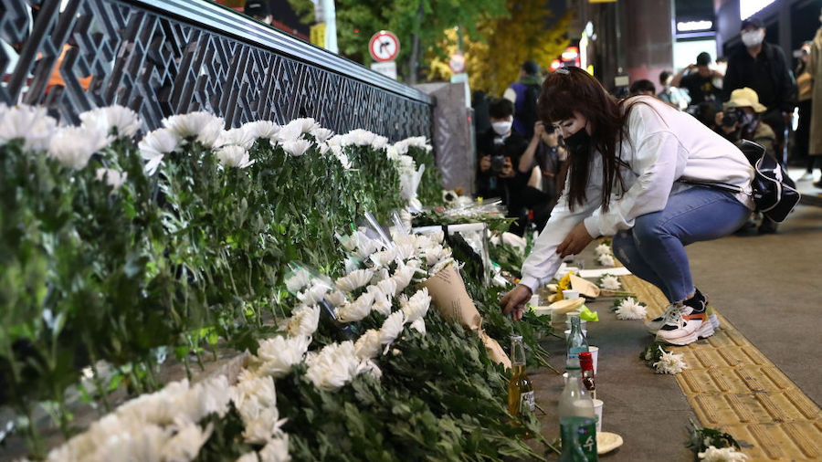 A woman lays flowers as she mourns at the street of a deadly stampede during a Halloween festival o...