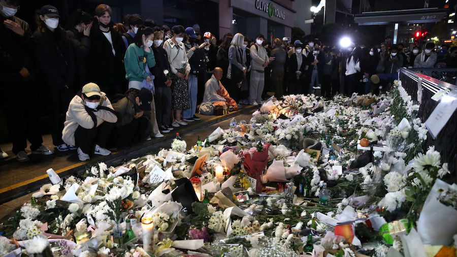 People pay tribute for the victims of the Halloween celebration stampede, on the street near the sc...