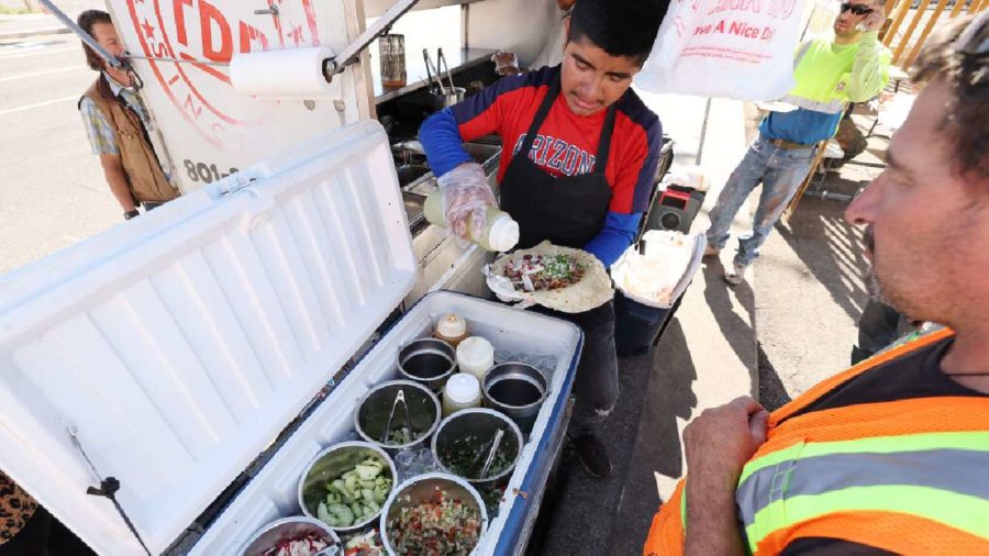 Lorenzo Lopez adds condiments to a customer's tacos at Tacos Don Rafa taco cart near the former Sea...