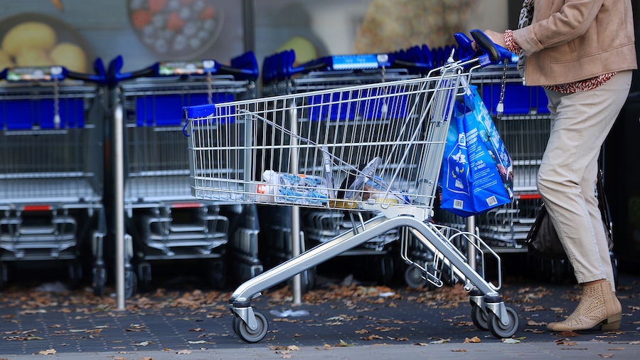A customer pushes a shopping cart and bags outside a supermarket operated by Aldi Einkauf GmbH & Co...