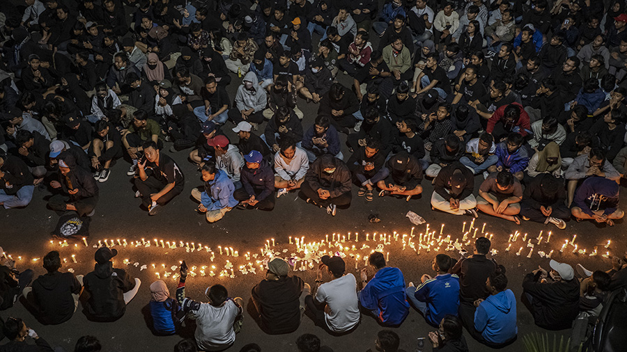 Arema football club supporters light candles as they pray for the victims on October 02, 2022 in Ma...