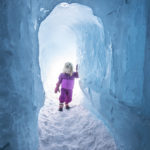 A child is walking through a tunnel within the ice castles. (AJ Mellor, Ice Castles)