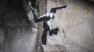 A gymnast doing a handstand painted on crumbling wall in black and white